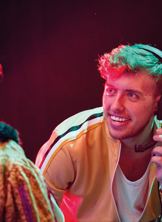Technical Theatre Arts student wearing a headset while talking to two other students