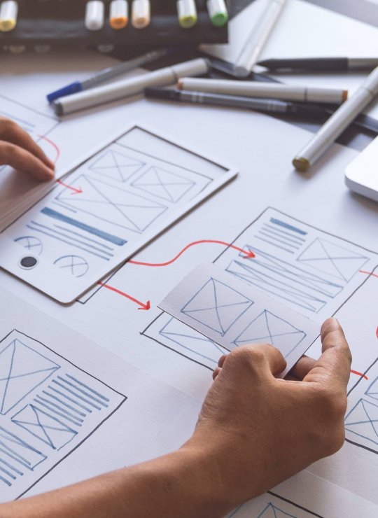 website layout plans on paper with hands and pens