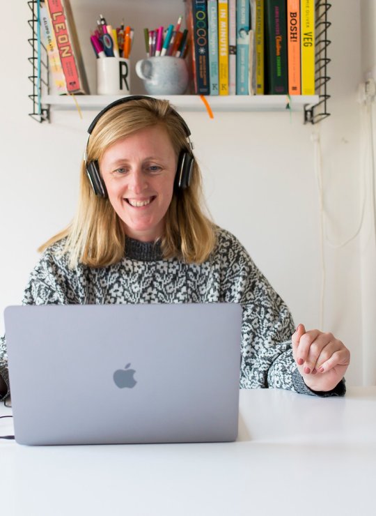 A woman smiling while looking at her laptop