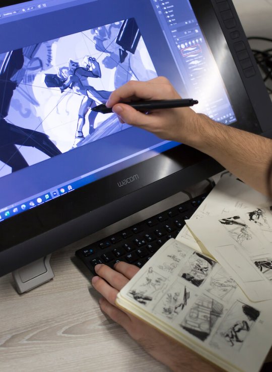 A hand holding a pen drawing game characters on a screen