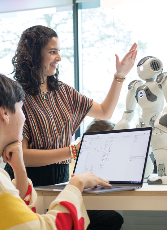 Two students stood together working on a robot