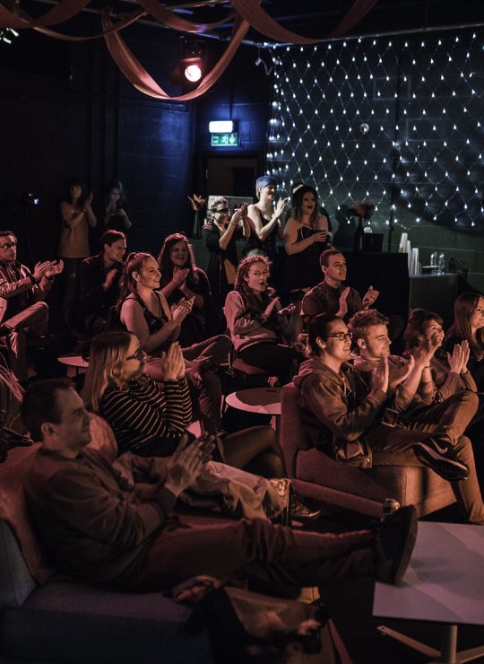 A busy venue with people watching a show and clapping