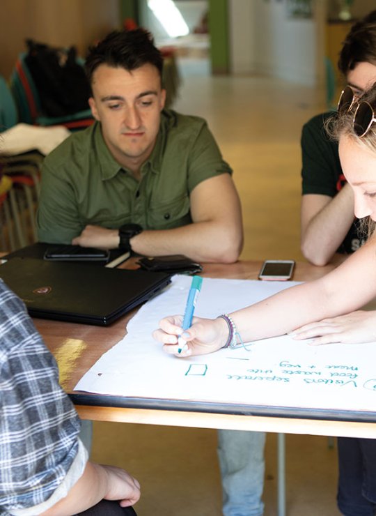 Students writing ideas down on a big pad on a table