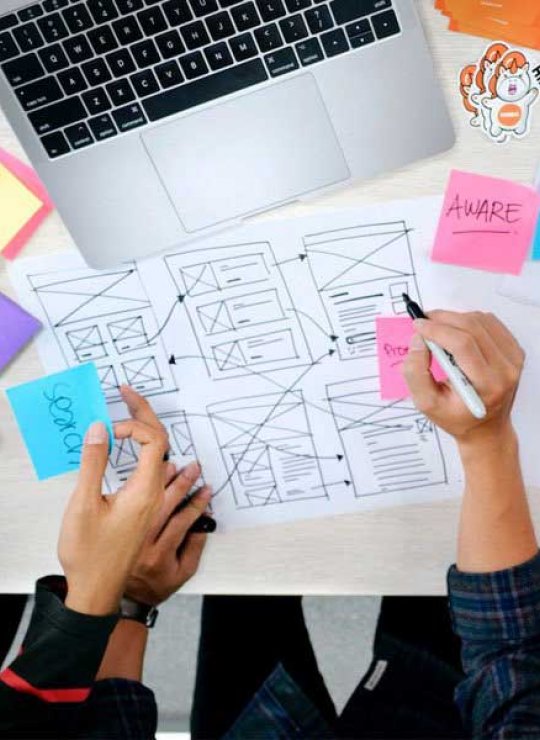 Students drawing UX Design diagrams on a piece of paper