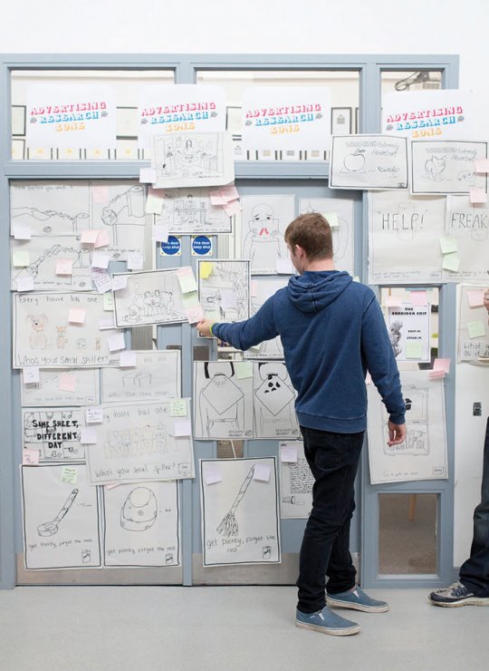 Students standing at a wall full of ideas written on paper