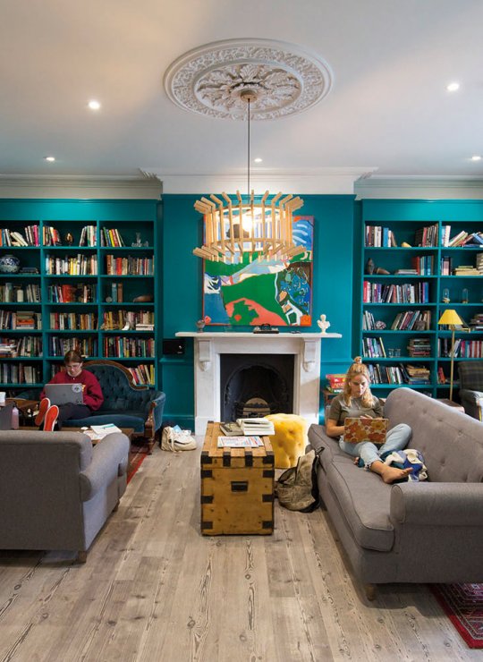Students sat on sofa in a room full of books