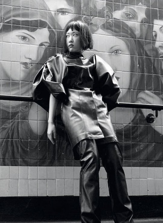 Fashion model posing in front of a mural of pre-raphelite women