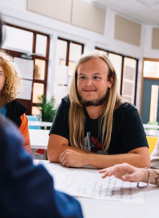 Students sat around a desk chatting