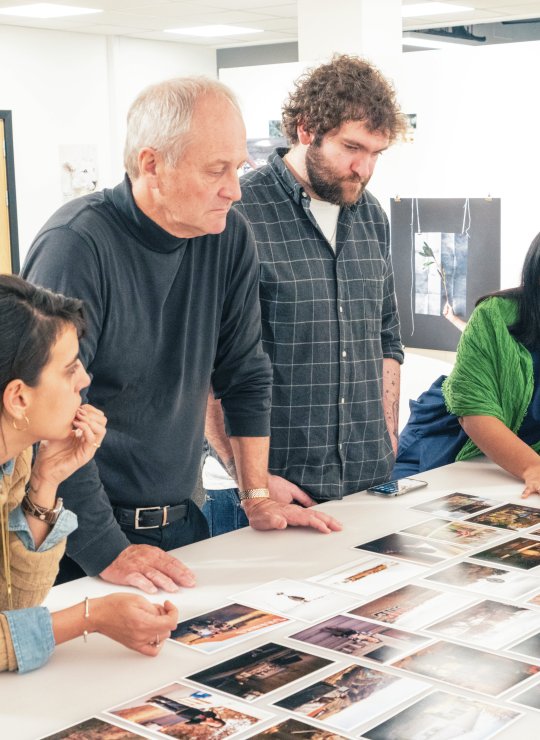 A group of people looking at photos on a table 
