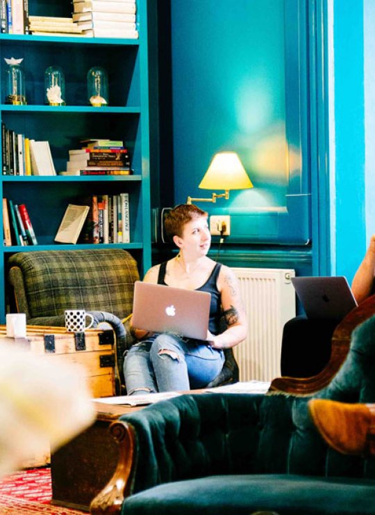 Falmouth University students sat on sofas in a blue room with bookshelves