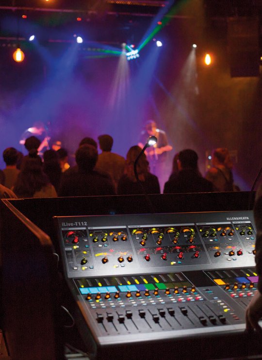 Student stood behind mixing desk while band play on stage