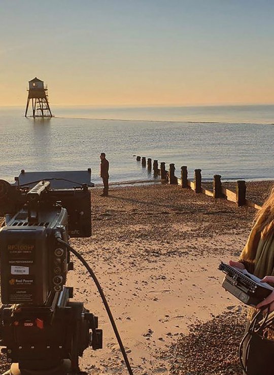 Student with film camera on beach at sunrise