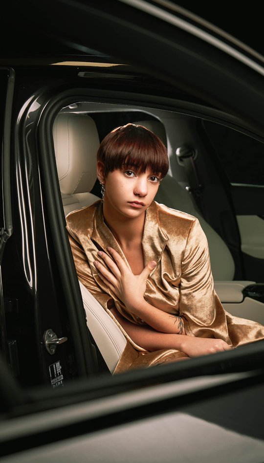A model wearing gold sitting in a black car