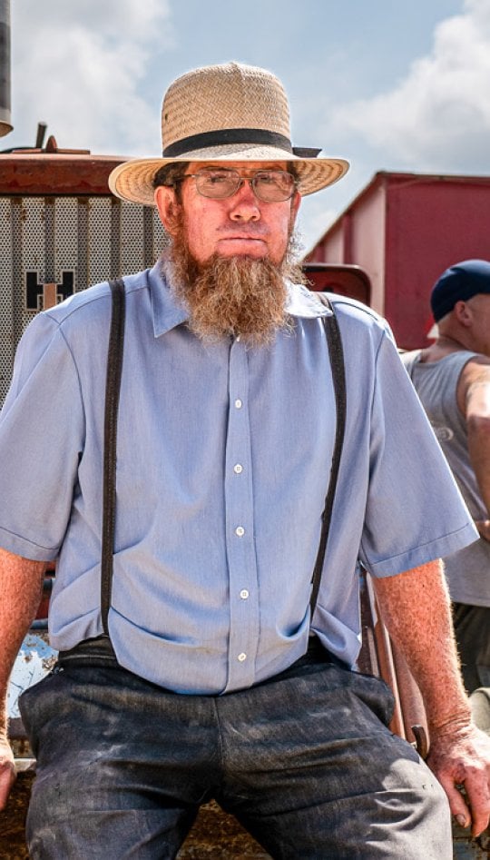 A man sitting at the front of a tractor with machinery around him