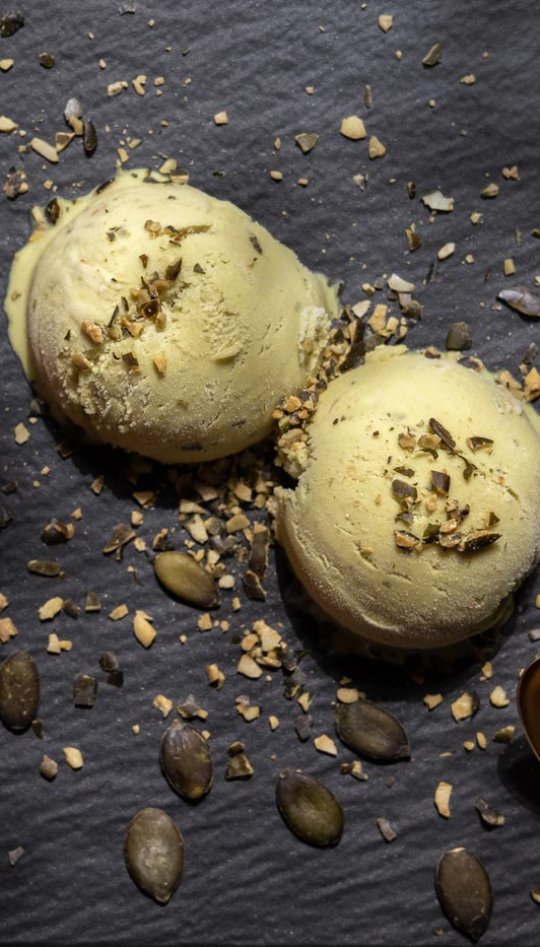 Two balls of ice cream with seeds, spoon and red fabric