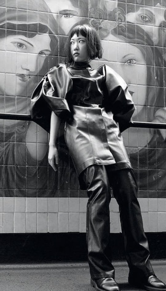 Fashion model posing in front of a mural of pre-raphelite women