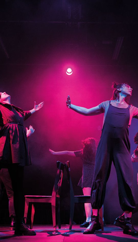 Actors on stage with arms spread