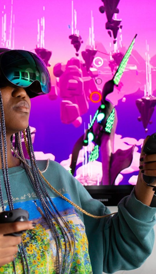 Falmouth University student wearing a VR headset in front of a pink screen