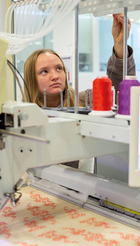 Textiles student working on machine
