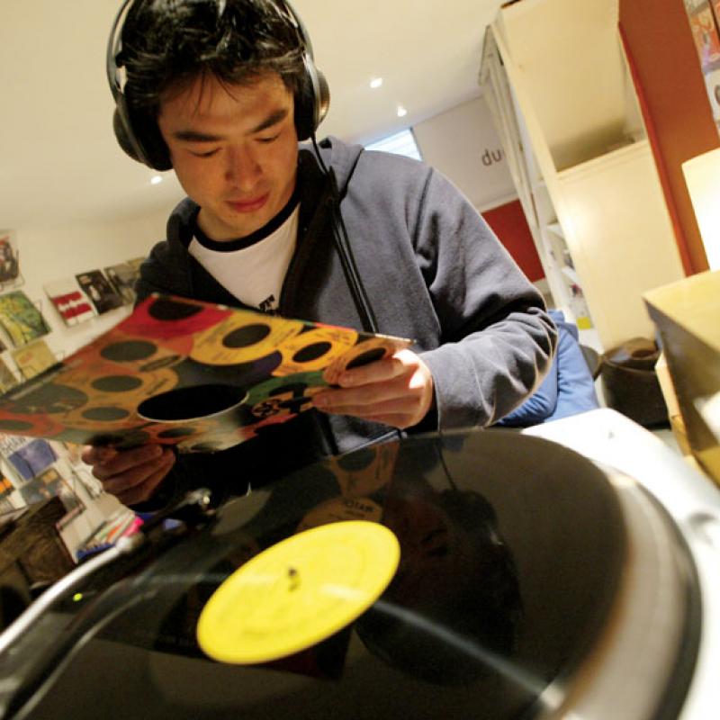 Student wearing earphones and putting record on record player.