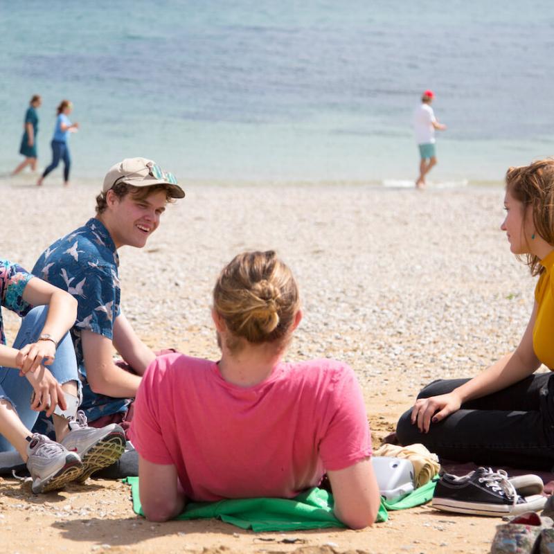 Falmouth University students relaxing on the beach