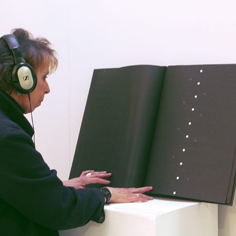 Person with headphones looking at a big black book