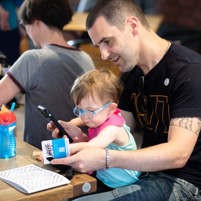 A man with a toddler on his lap with a phone