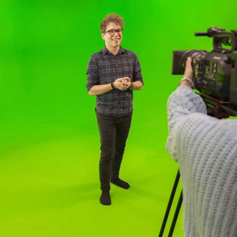 Student being filmed with bright green screen studio.