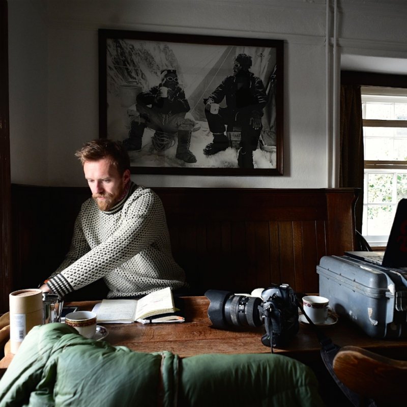 Portrait of Huw at table with camera, coffee and journal