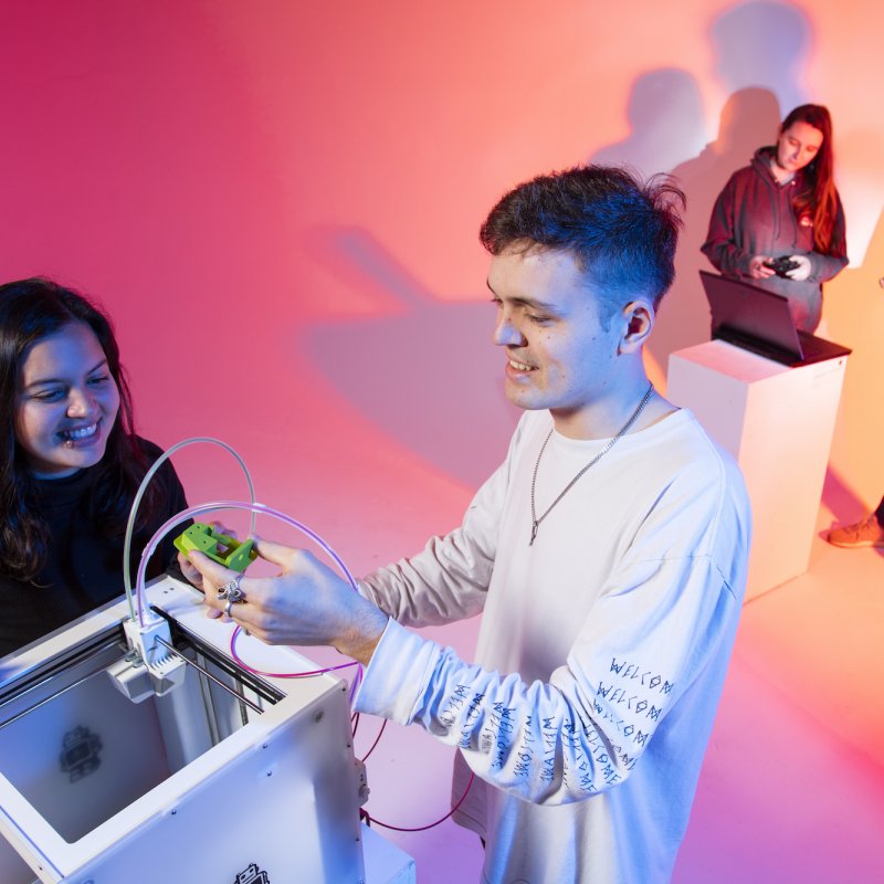 Male student and female student playing with a white box and a green robotic device