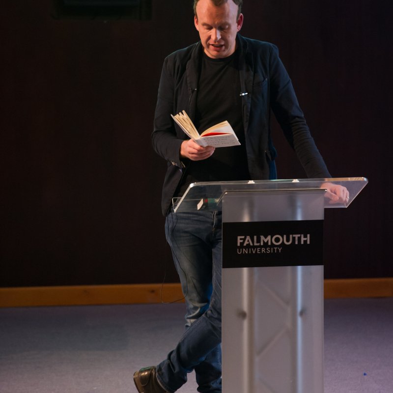 Writer, Matt Haig, reading from book on stage.