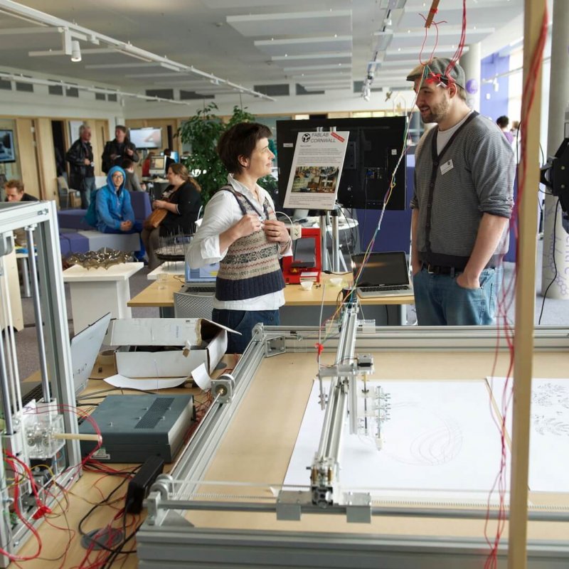 Lecturers stood next to an electronic drawing machine at the AIR building on Penryn campus.