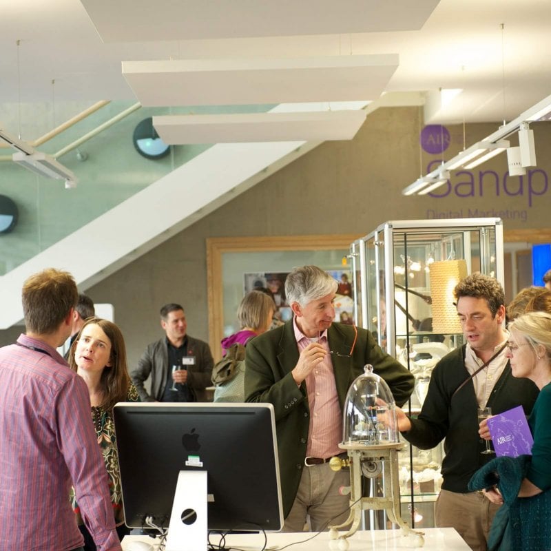 People standing round and chatting at an exhibition at Falmouth University