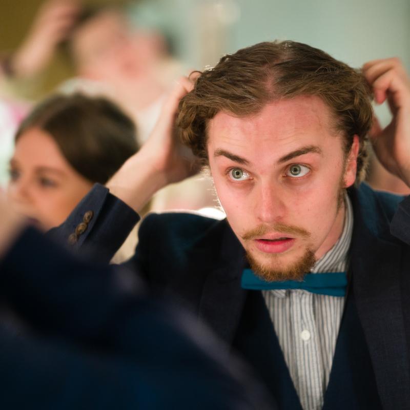 Falmouth University acting student looking in the mirror, wearing a jacket and bow tie
