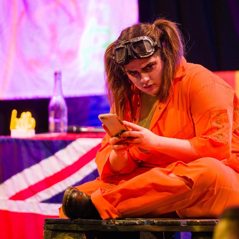 A girl wearing an orange jumpsuit looking at her phone