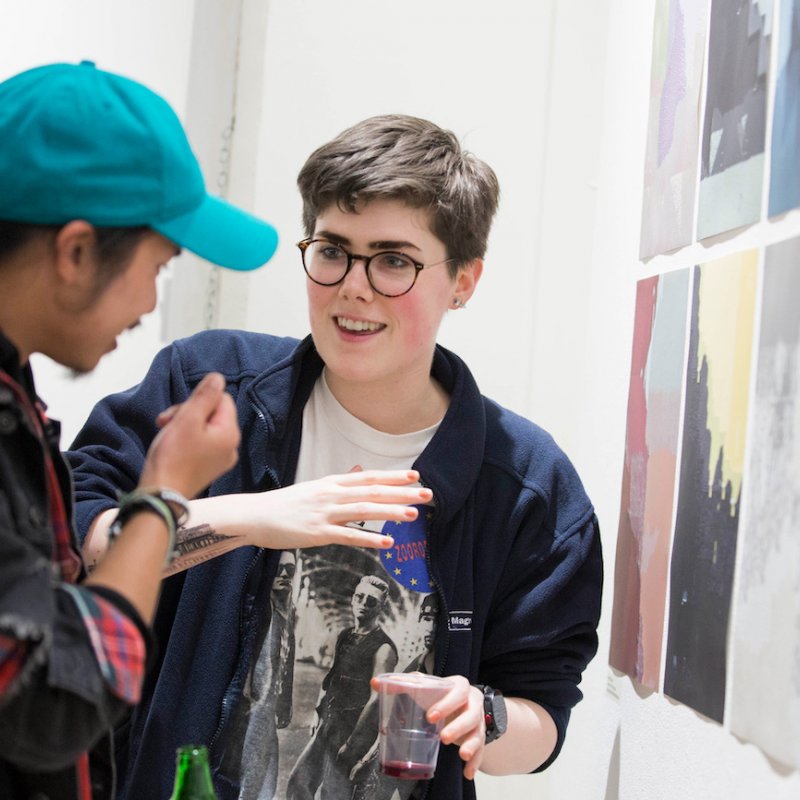 Two Falmouth University students discussing images at an exhibition.