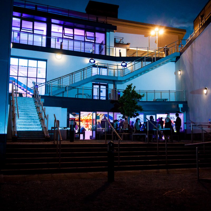 AMATA building with external staircases lit up in blue and purple.
