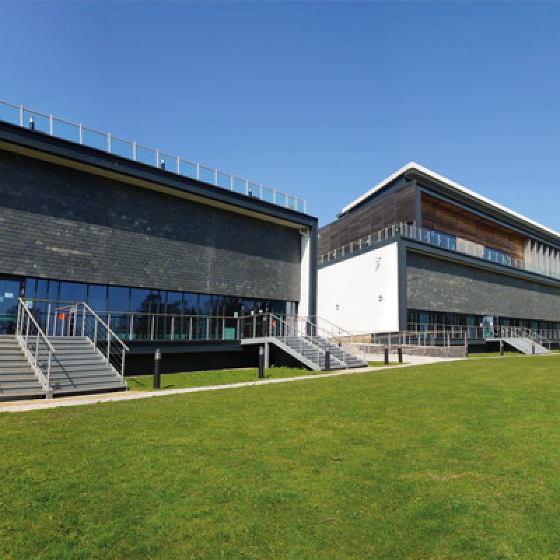 Exterior of the AMATA building on Penryn Campus with grass and blue sky