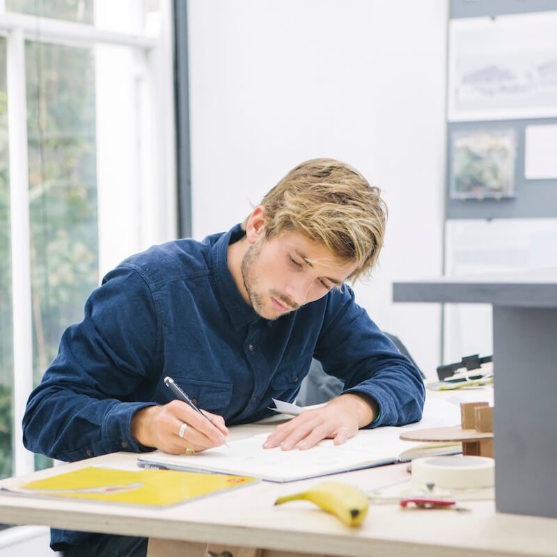 Falmouth University Architecture student working at a desk, wearing a blue shirt