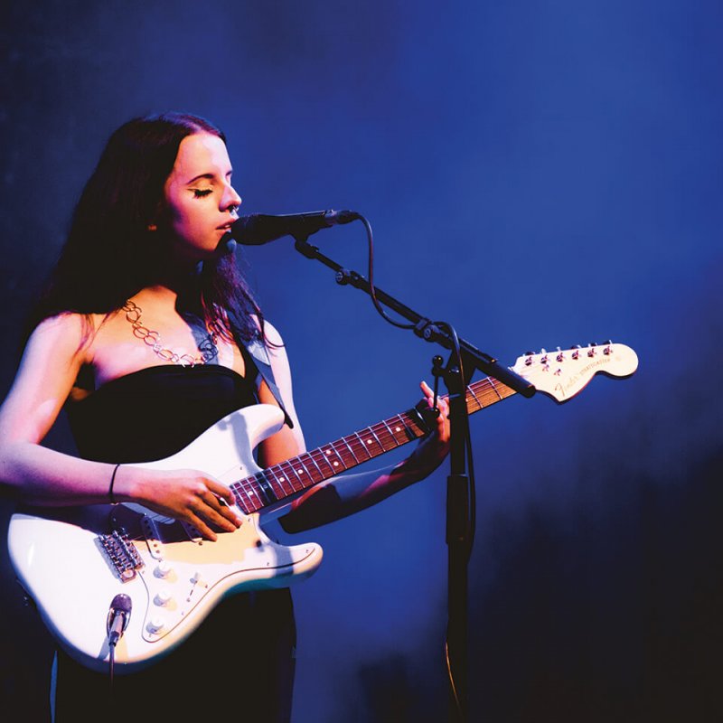 Falmouth Popular Music student singing and playing guitar on stage 