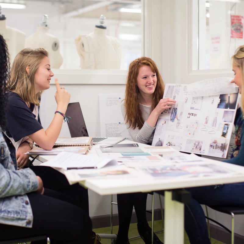 Falmouth University students discussing work on boards in a studio.