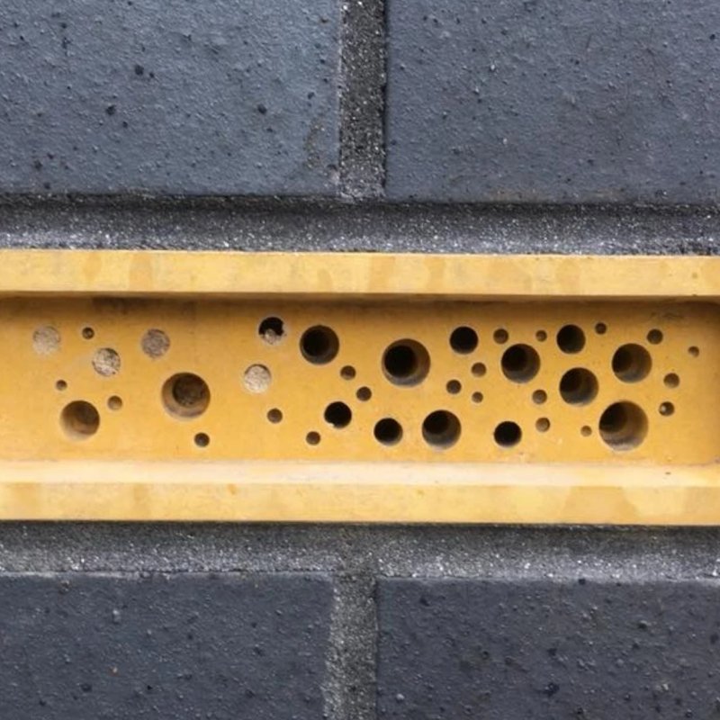 A yellow Bee Brick in a black wall