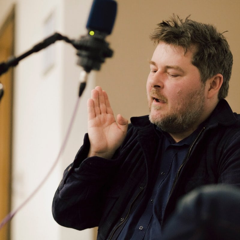 Man talking into microphone with hand in the air.