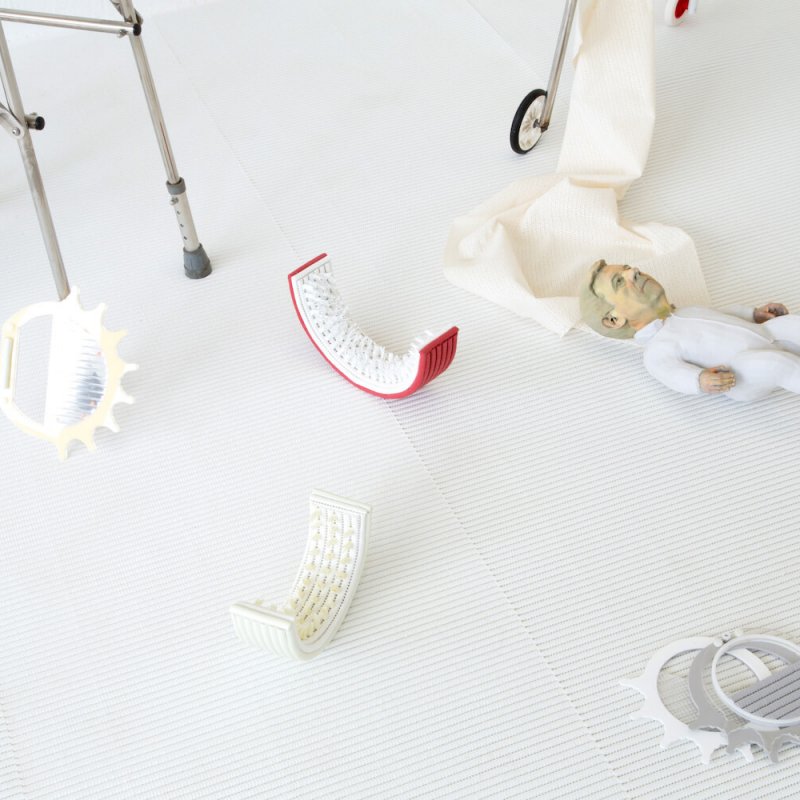 Artwork grown man with a baby size body in white romper suit, wheelchair and crutches view.