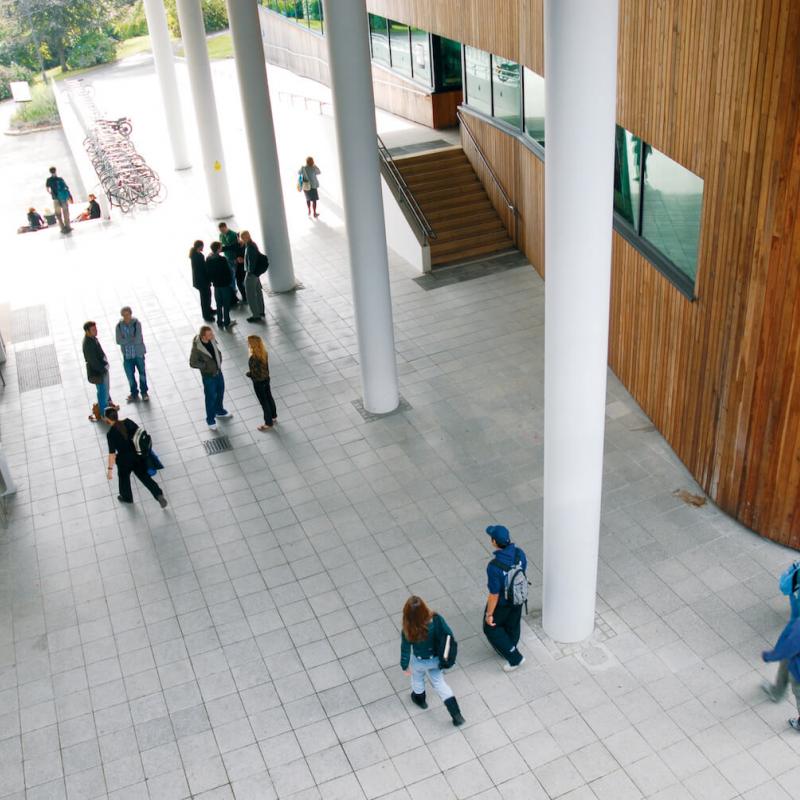 View down onto Penryn campus foyer and people walking and chatting.