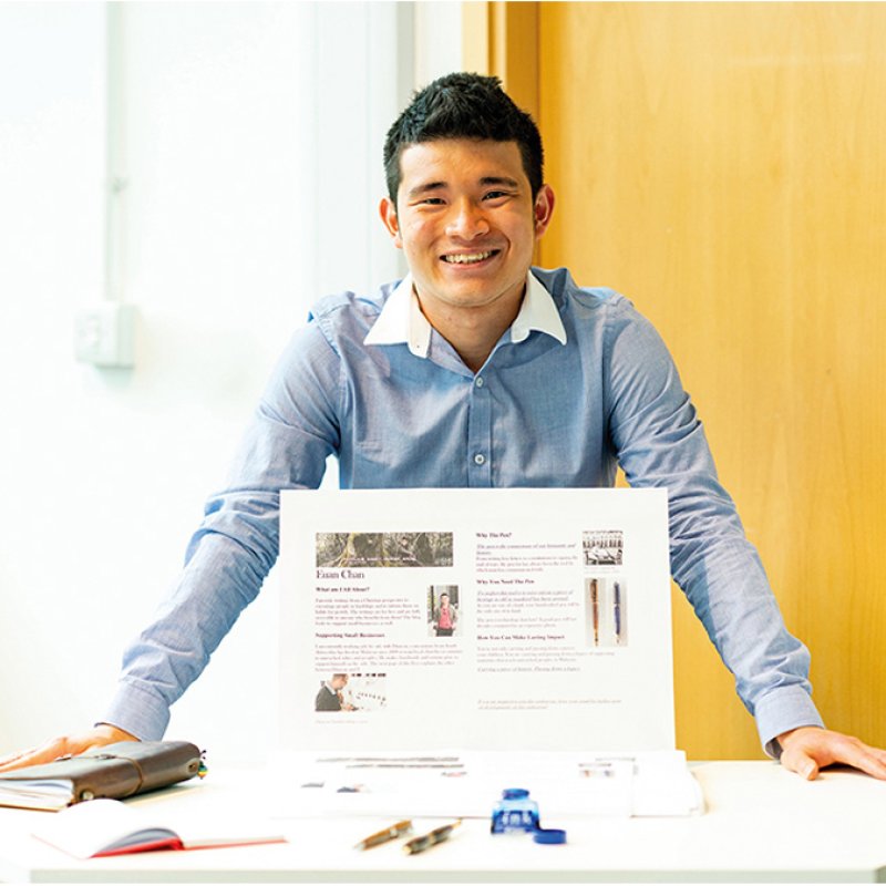 Business & Entrepreneurship student standing at a display table, smiling