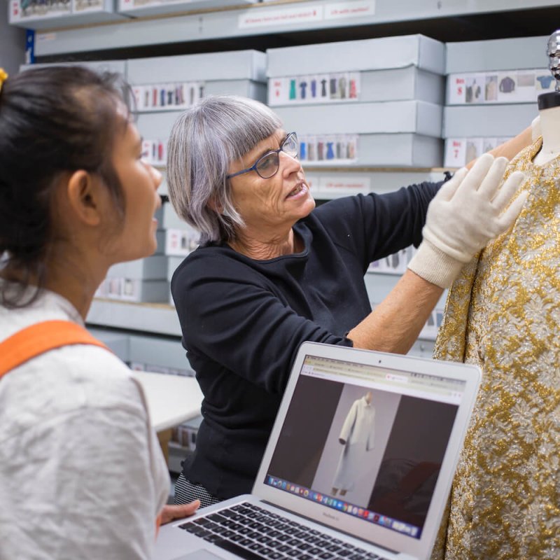 Costume Design student and lecturer examining a gold coat