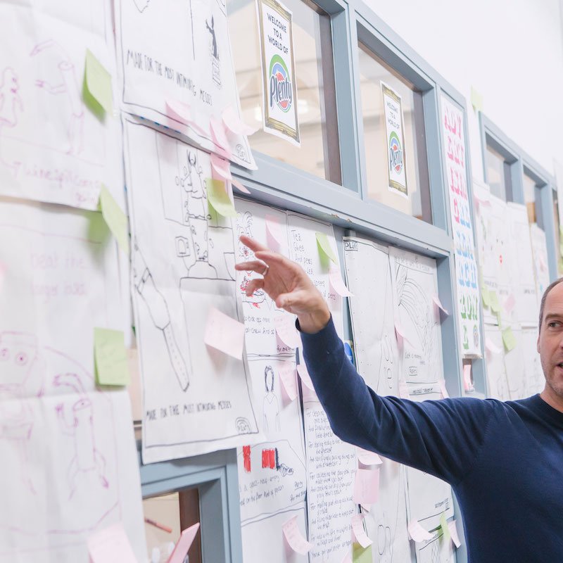 Falmouth University Creative advertising lecturer pointing to ideas wall