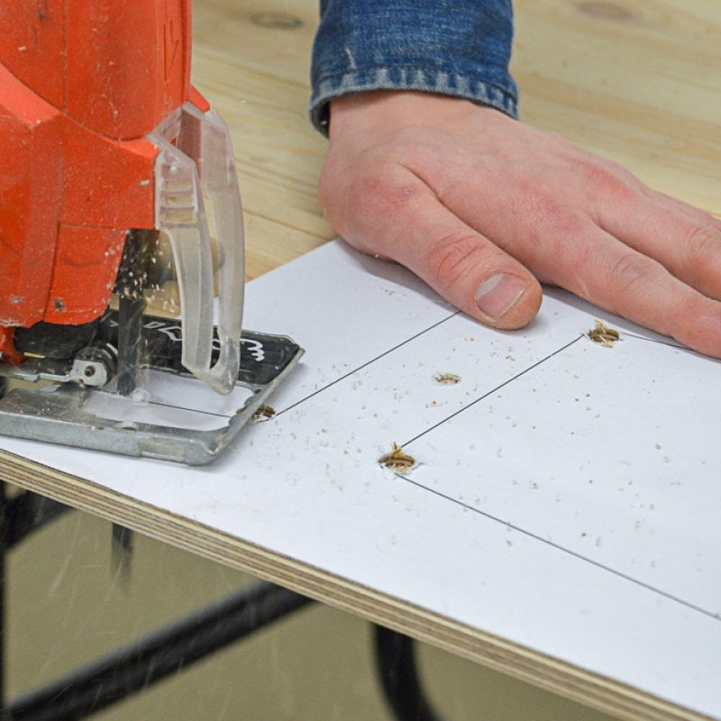 A person using a jigsaw to cut wood
