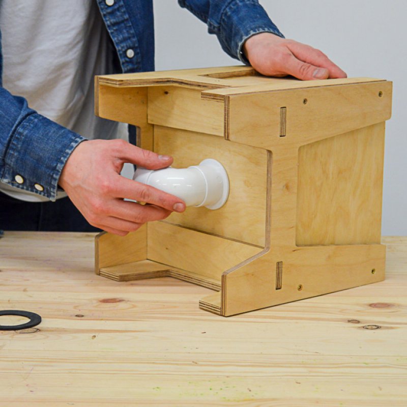 A person putting a white pipe on a wooden box